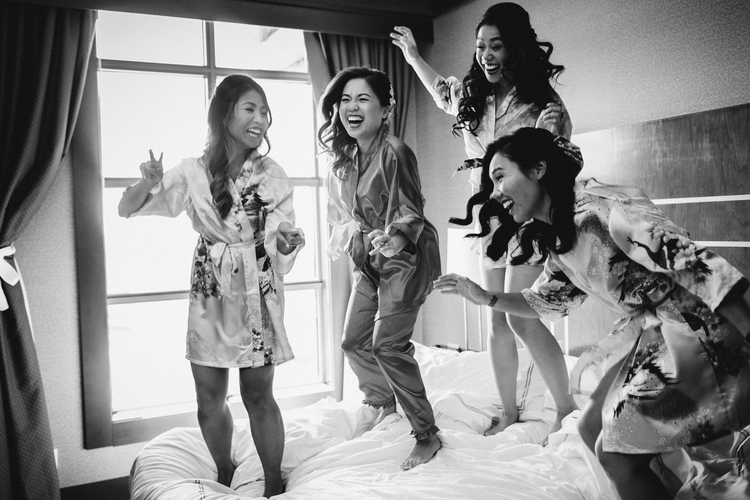 bride and bridesmaids jumping on bed candid river rock casino hotel wedding photography